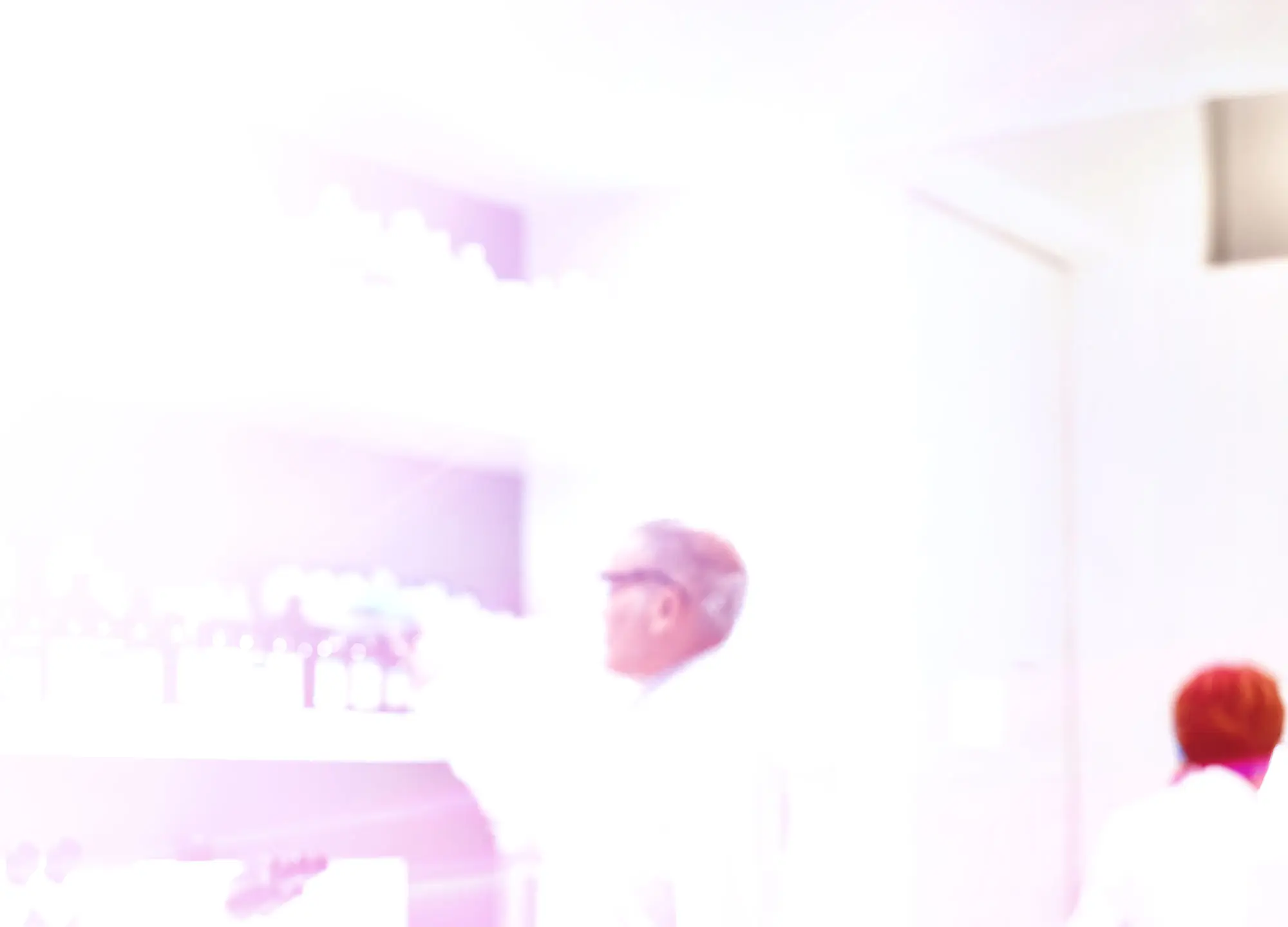 Blindingly bright image of a person in light clothing and headwear, standing indoors.