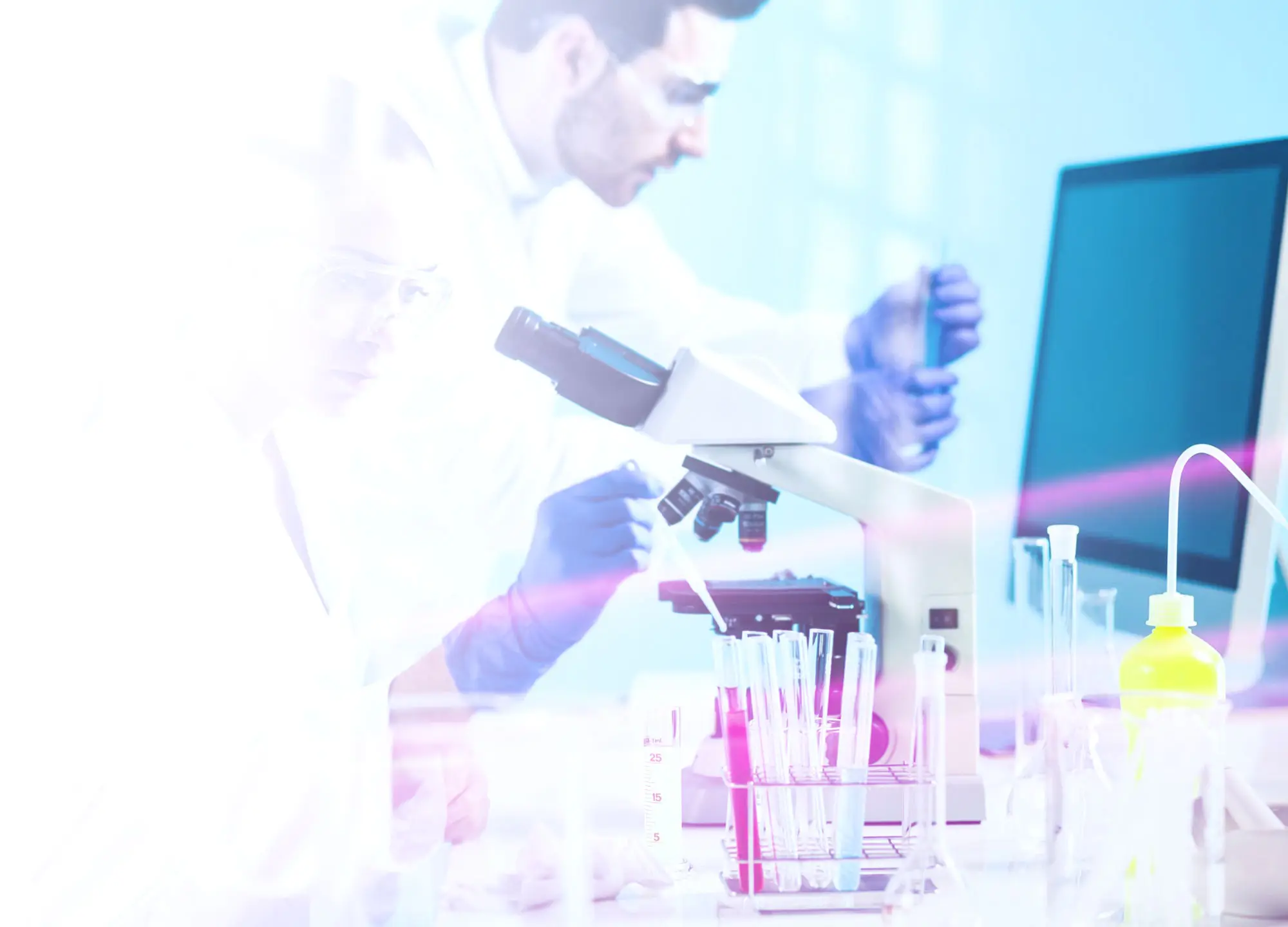 Scientist in lab coat and gloves works with a microscope and test tubes in a bright, modern laboratory.